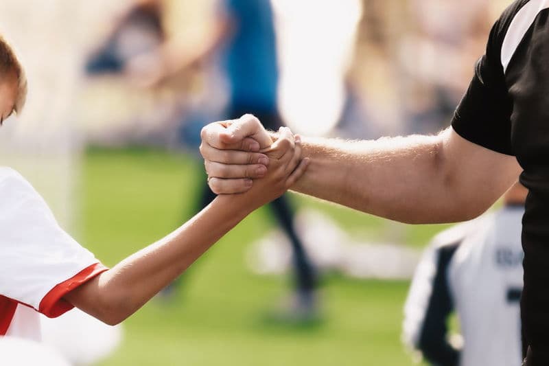 a coach and a player shake hands in solidarity